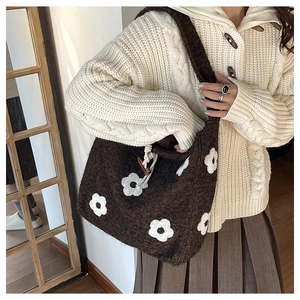 Close-up of brown knit tote bag featuring white floral patterns and wooden toggle button