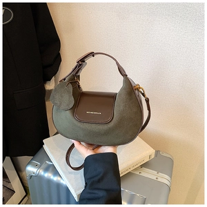 Detail of dark green suede hobo bag with brown leather flap and heart-shaped charm