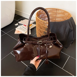 Detailed view of deep brown glossy tote bag featuring slim shoulder straps and metal buckle