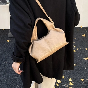 Detail of beige pleated cloud bag with soft leather texture and adjustable shoulder strap