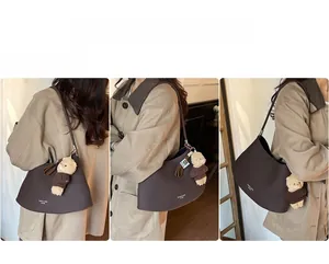 Detail view of brown leather crescent underarm bag with cute bear charm on model