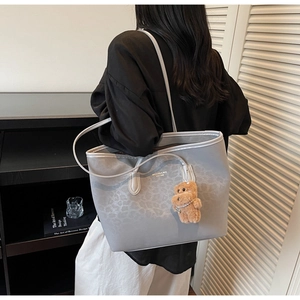 Light gray leopard print tote bag with bear charm shown in a lifestyle model shot