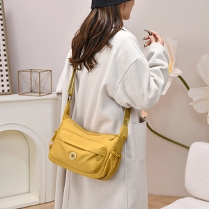 Close-up of bright yellow nylon crossbody bag with multi-pockets and logo detail