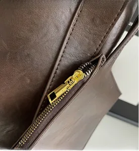 Close-up of smooth gold metal zipper on premium dark brown leather tote bag detail