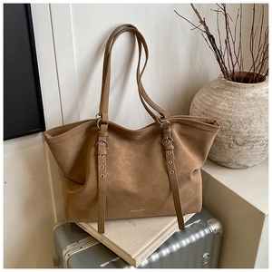 Detail of vintage brown leather tote bag with dual shoulder straps and metallic eyelets