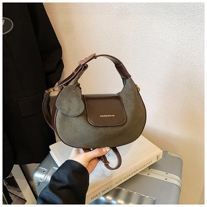 Detailed shot of dark green suede half-moon bag with gold buckle and heart charm detail