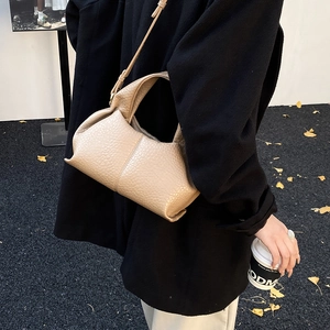 Close-up of beige cloud bag with pebble leather texture and autumn leaves background