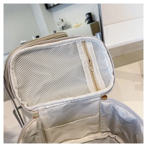 Dettaglio interno della borsa cosmetica beige con tasca a rete e divisori elastici