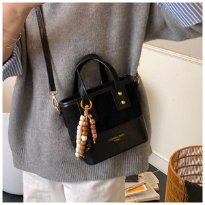 Detail of black patchwork shoulder bag with gold hardware and wooden bead charm
