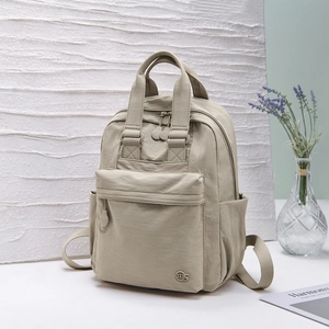 Detail of light grey nylon backpack showing durable top handle and smooth zipper pockets