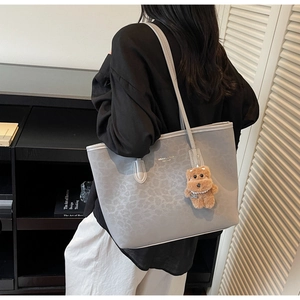 Close-up of grey leopard pattern tote bag with cute brown plush bear charm detail