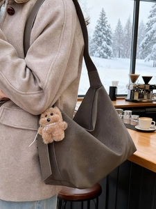 Borsa tote in pelle opaca grigia con ciondolo a cucciolo in un bar innevato