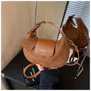 Detail of caramel suede crescent bag with heart charm and smooth leather texture