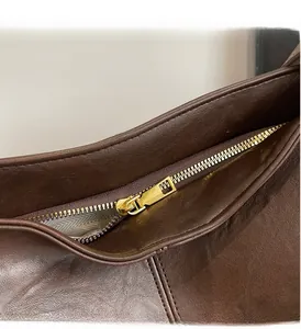 Detail of smooth gold zipper and herringbone fabric lining on a brown leather tote bag