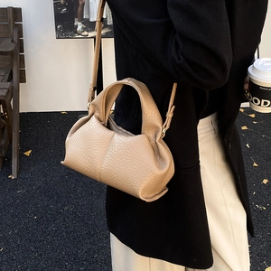 Detail of beige cloud bag with lychee texture and pleated design in outdoor setting