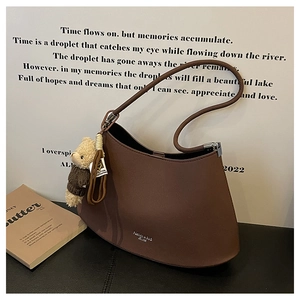 Close-up of brown crescent hobo bag with teddy bear charm on a stylish display
