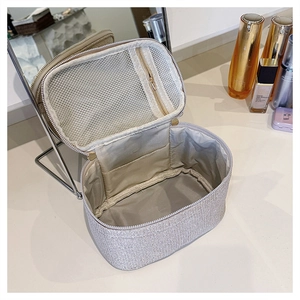 Dettaglio interno di una borsa per cosmetici in paillettes argento con tasche a rete