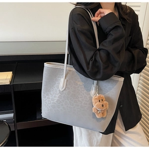 Close-up of gray leopard embossed tote bag featuring a cute brown plush bear charm