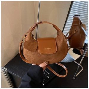 Detail view of brown matte leather crossbody bag with heart charm and side mirror reflection