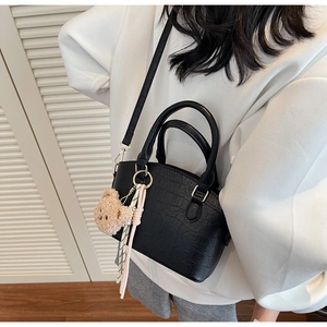 Detail of black crocodile pattern bucket bag with cute bear charm and striped silk scarf