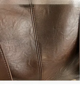 Detail of premium brown faux leather with reinforced double stitching and natural texture