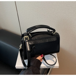 Gros plan du sac en cuir froissé noir avec détails dorés et poignée supérieure