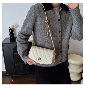 Détail du sac bandoulière beige matelassé avec fermoir doré et bandoulière chaîne