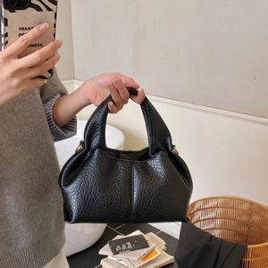 Detail of black textured leather handbag with gold hardware and half-moon structure