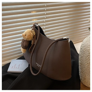 Detail of dark brown faux leather underarm bag with cute plush bear charm and silver hardware