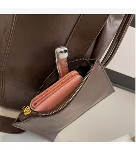 Detail of dark brown tote bag featuring a detachable matching pouch with metal zipper
