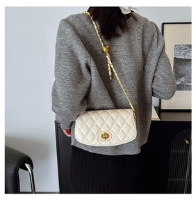 Détail du sac bandoulière blanc matelassé avec fermoir doré et chaîne porté par un mannequin