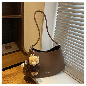 Detail of dark brown lychee leather shoulder bag with bear plush charm and logo