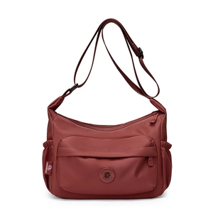 Detailed view of dark red nylon crossbody bag with multi-pocket design and adjustable strap