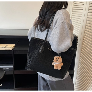 Detail of black tote bag with leopard print side and brown bear plush charm