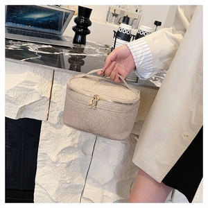 Dettaglio borsa da trucco oro champagne con finitura glitter e doppia cerniera in metallo