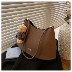 Detailed texture of brown litchi grain leather shoulder bag with cute bear charm