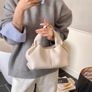 Close-up of cream textured leather handbag with elegant gold hardware detail