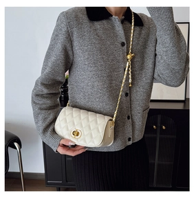 Détail du sac à bandoulière matelassé blanc avec chaîne dorée et fermoir rotatif