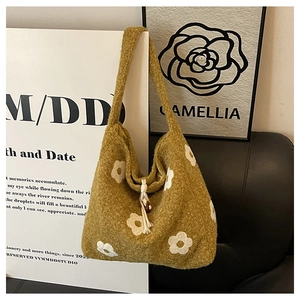 Detailed close-up of green plush tote bag featuring white camellia flower patterns