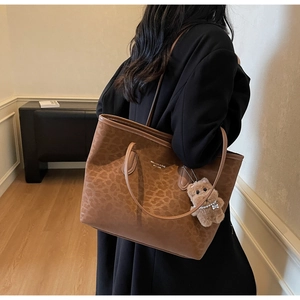 Detail of leopard print tote bag with plush bear charm and embossed PU leather texture