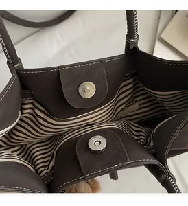 Dettaglio borsa tote marrone scuro con fodera a righe e chiusure magnetiche