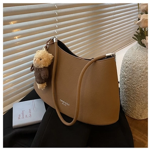 Detail of brown hobo bag with a teddy bear pendant and textured leather finish