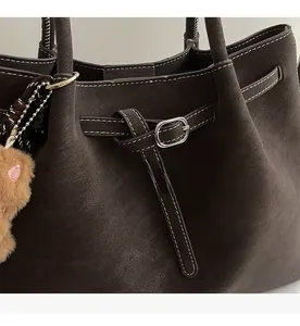 Dettaglio della borsa tote in pelle testa di moro con cuciture bianche e charm orsetto