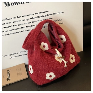 Detailed close-up of burgundy plush tote bag with white flower patterns on dark surface