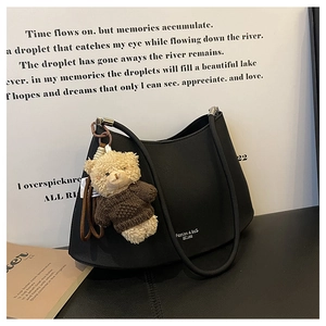 Detail of black crescent moon shoulder bag with cute teddy bear plush charm attachment
