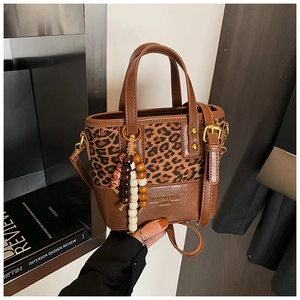 Vue détaillée du sac seau à imprimé léopard avec finitions en cuir marron et breloque