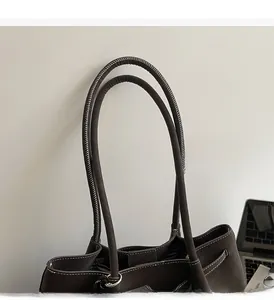 Dettaglio dei manici tondi con cuciture bianche su borsa tote marrone scuro