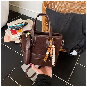 Detail of dark brown patchwork tote bag with suede top and vintage wood bead charm