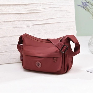 Detailed close-up of water-resistant burgundy nylon crossbody bag with textured strap