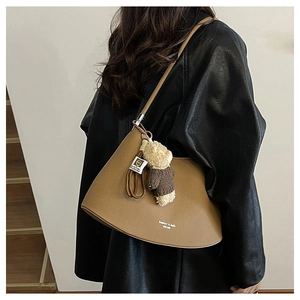 Detail of caramel faux leather shoulder bag with cute teddy bear charm and gold lettering